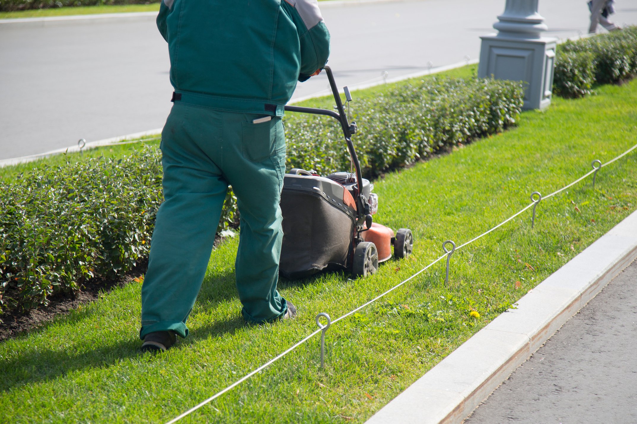 a service Worker mows the lawn with a lawn mower.